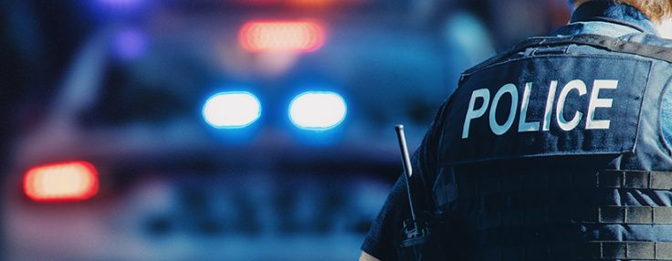 american,policeman,and,police,car,in,the,background